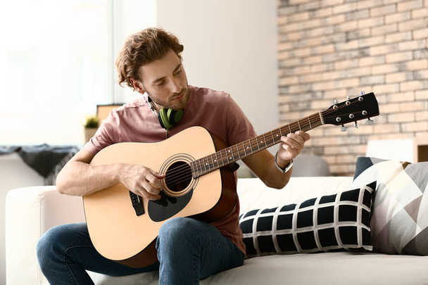 Young man playing guitar at home - Foto, afbeelding