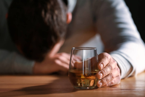 Een bewusteloze dronken man met een glas whisky aan tafel. - Foto, afbeelding