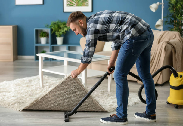 Young man removing dirt from floor with vacuum cleaner - Fotografie, Obrázek