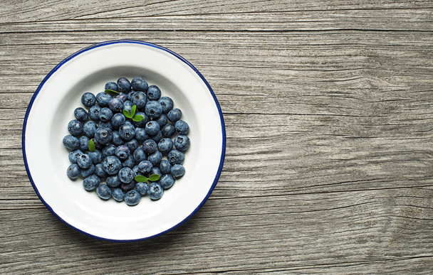 Fresh Blueberries in a bowl on wooden background - Photo, image