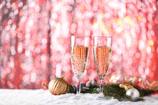 Copas de champán y decoración navideña sobre nieve contra luces borrosas
 - Foto, imagen