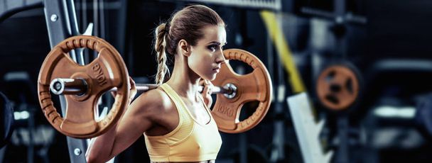 young fitness woman execute exercise with barbell in gym, horizontal photo - Fotografie, Obrázek