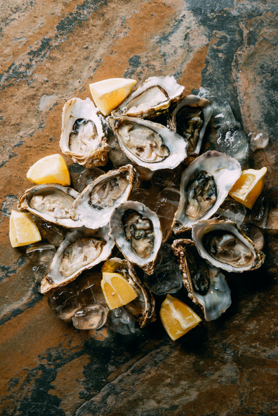food composition of oysters, lemon pieces and ice on grungy tabletop - Фото, зображення