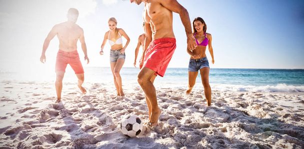 Cheerful friends playing football at beach - Fotoğraf, Görsel