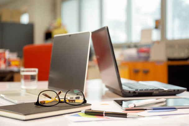 Brýle na pracovní stůl s papírovou tabuli a laptop na obchodní schůzku stůl - Fotografie, Obrázek