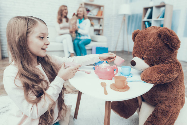 Young Girl Playing with Big Plush Bear at Home. Smiling Women. Sitting on Sofa. Happy Family. Sitting at Home. Tea Party at Home. Small Table. White Carpet. Girl with Cup. Fun Indoor. - Fotoğraf, Görsel