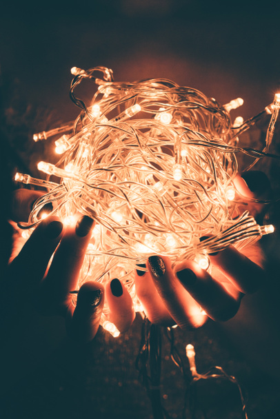 cropped shot of woman holding bright festive lights in hands - Foto, imagen