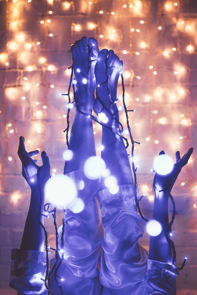Μερική άποψη της γυναίκας στην πιτζάμες με γιορτινά φώτα των Χριστουγέννων γύρω από - Φωτογραφία, εικόνα