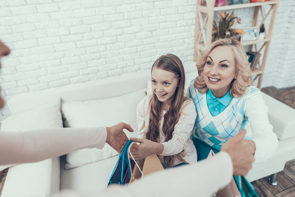 Mother Giving Packages with Gifts to Happy Family. Mother with Daughter. Smiling Women. Celebration Concept. Happy Family. Sitting at Home. Holiday in March. White Sofa. Happy Daughter. - Foto, imagen