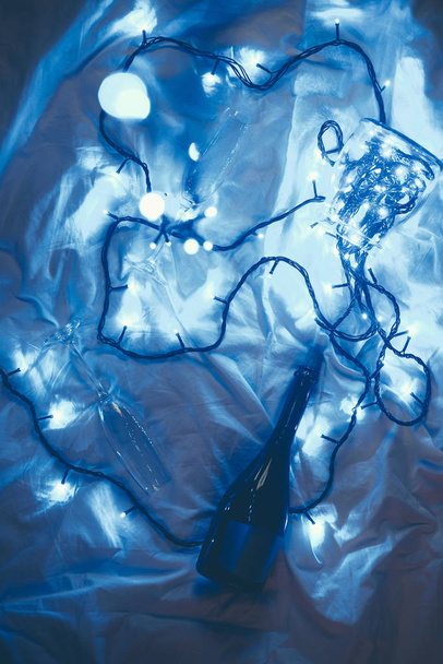 plano con luces festivas de invierno, botella de champán y vidrio en la cama
 - Foto, Imagen