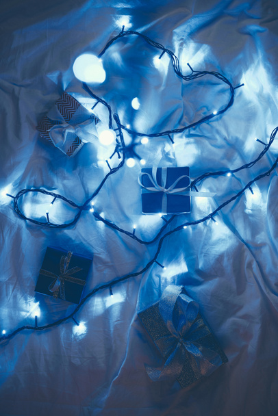 piso con regalos de Navidad envueltos y luces festivas en la cama
 - Foto, Imagen