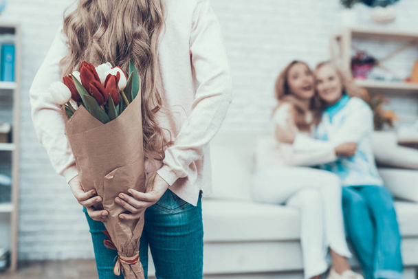 Girl Presenting Bouquet of Tulips to Smiling Mother. Mother with Daughter. Smiling Women. Celebration Concept. Happy Family. Sitting at Home. Red Flower. White Flower. Holiday in March. Mother's Day. - Fotoğraf, Görsel