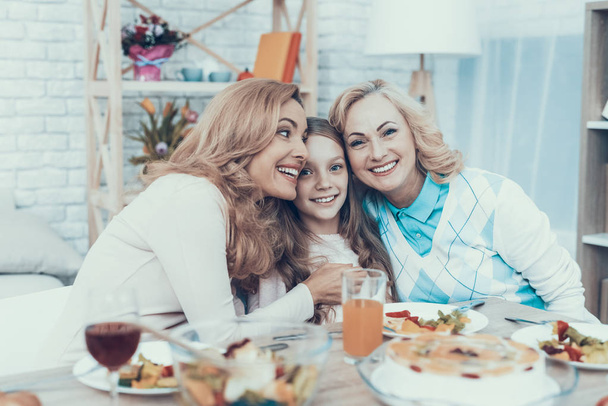 Family Celebrating Daughter's Birthday at Home. Cake on Table. Happy Family. Mother with Daughter. Smiling Women. Smiling Grandmother. Celebration Concept. Glass of Wine. Hugging Together. - 写真・画像