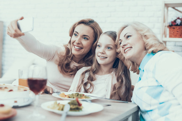 幸せな家族の家で Selfie したりして祝います。テーブルの上のケーキ。幸せな家族。娘を持つ母です。笑顔の女性。祖母は笑ってください。お祝いのコンセプトです。スマート フォンを使用しています。写真を撮る. - 写真・画像