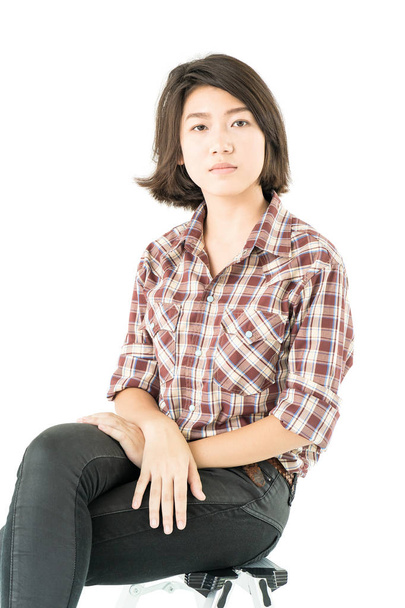Jovem mulher em uma camisa xadrez posando em estúdio em branco
  - Foto, Imagem