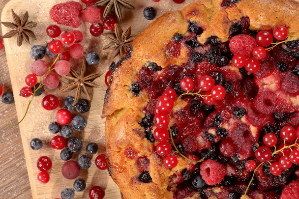 Home-cooked tasty pie with raspberry blueberry currant cranberry on brown board - Foto, imagen