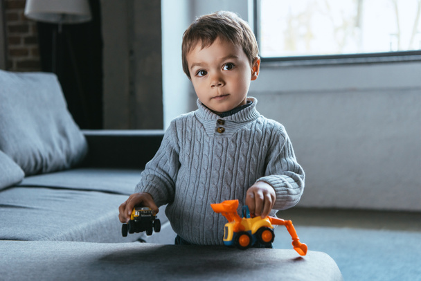 joyful little boy playing with toy cars in living room at home - Fotografie, Obrázek