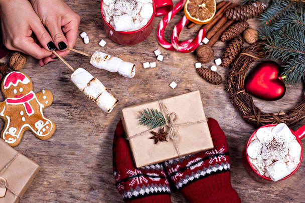 Cadeau, cônes, cadeaux, café, cacao. Noël, fond Nouvel An. La main d'une femme tient une tasse. Hiver, Nouvel An, Noël nature morte.  - Photo, image