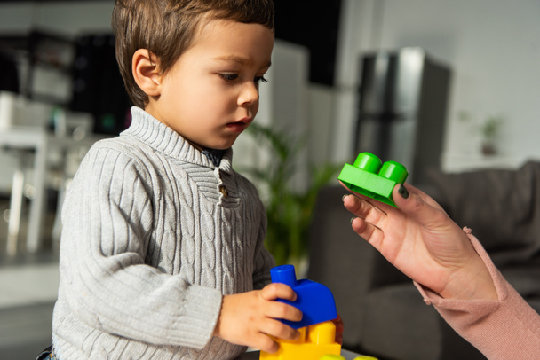 partial view of woman playing plastic blocks with little son at home - Foto, Bild