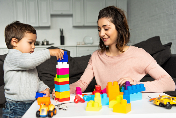 selective focus of mother and little son playing with colorful plastic blocks at home - Фото, изображение