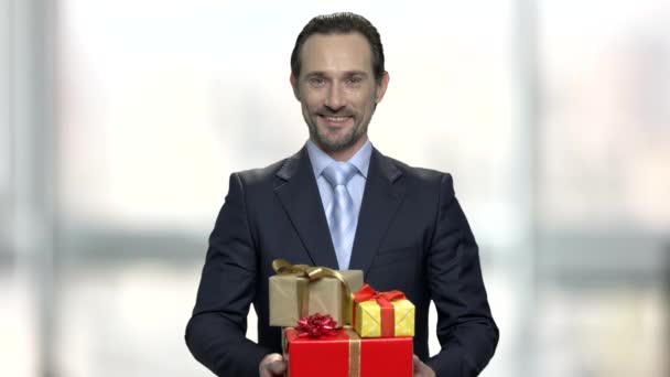 Lächelnder Geschäftsmann mit Stapel von Geschenkboxen. - Filmmaterial, Video