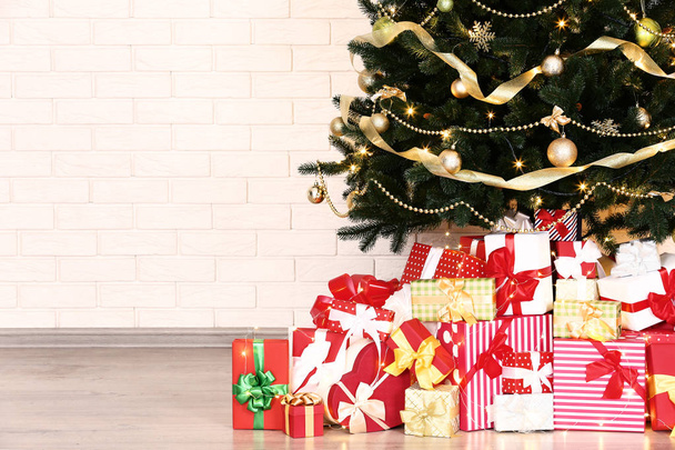 Christmas tree with decorations and gift boxes on brick wall background - Фото, изображение