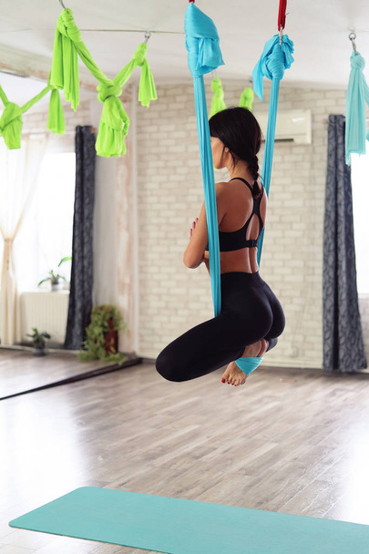 Adult woman practices anti-gravity yoga position in studio - Zdjęcie, obraz