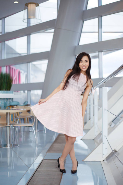 young smiling asian woman in pink dress posing in cafe - Foto, immagini