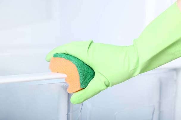 Hand in glove with sponge cleaning refrigerator - Foto, afbeelding