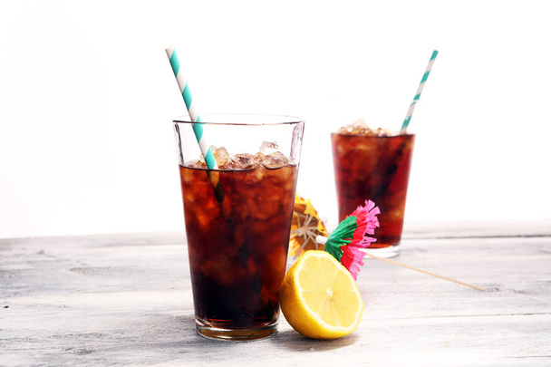 Softdrink with ice cubes, lemon and straw in glass. - Photo, Image