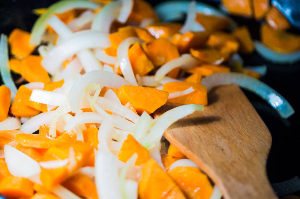 fein gehackte Zwiebeln und Karotten in einer erhitzten Pfanne, Nahaufnahme - Foto, Bild