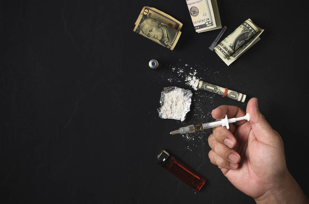 Мужчина держит шприц для инъекций наркотиков и кокаин.
 - Фото, изображение