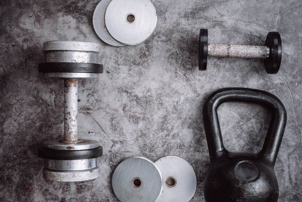 Fitness or bodybuilding concept background. Old iron dumbbells and Kettlebell on grey, conrete floor in the gym.  Top view. Healthz lifestyle. - Fotó, kép
