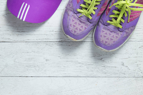 Urheilu tasainen lay violetti kengät ja korkki valkoinen puinen tausta copyspace tekstin. Käsitteen terveellinen elämäntapa ja ruokavalio
. - Valokuva, kuva