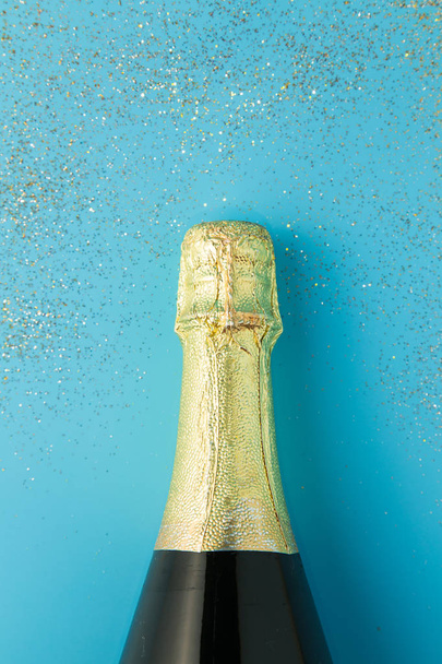Plochý uspořádání oslav, láhev šampaňského na modrém podkladu s glitrem. - Fotografie, Obrázek