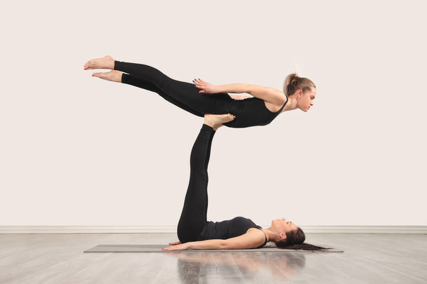 zwei schlanke Mädchen machen Yoga drinnen - Foto, Bild