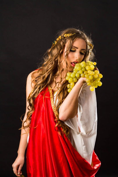 Ancient goddess with a bunch of grapes isolated on a black background - Zdjęcie, obraz