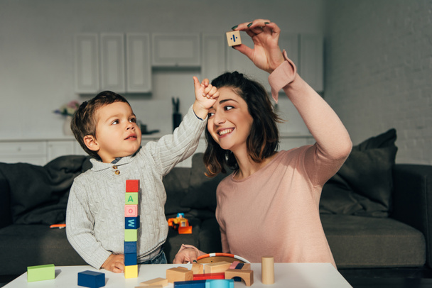 kid and his mother playing blocks wood tower game at home - Foto, Imagen