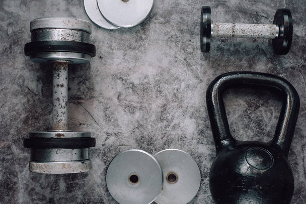 Fitness or bodybuilding concept background. Old iron dumbbells and Kettlebell on grey, conrete floor in the gym.  Top view. Healthz lifestyle. - Photo, Image