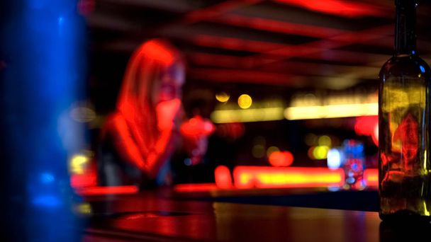 Pretty young female with glass drinking cocktail at bar, blurred background - 写真・画像
