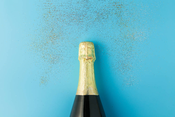 Couché plat de célébration, bouteille de champagne sur fond bleu avec paillettes
. - Photo, image