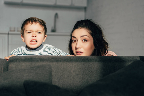 beautiful mother and emotional little son sitting on sofa at home - Fotoğraf, Görsel