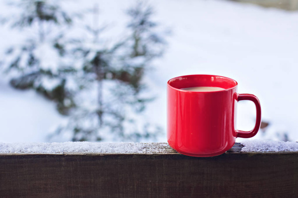 Cup with coffee, tea on the background of the winter landscape.  A cup with a hot drink on the background of the winter forest. the table outdoor in the winter. Winter time concept. - Foto, afbeelding
