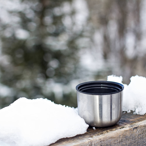 Cup of Thermos on the background of the winter landscape.  - Foto, afbeelding