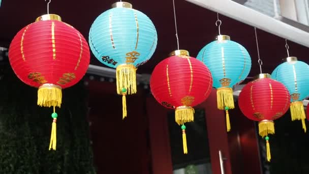 Le lanterne cinesi ondeggiano nel vento nel pomeriggio. Luci di carta orientale di colori rossi e blu ondeggiano con il vento sul tetto di un edificio di giorno sulla strada
 - Filmati, video