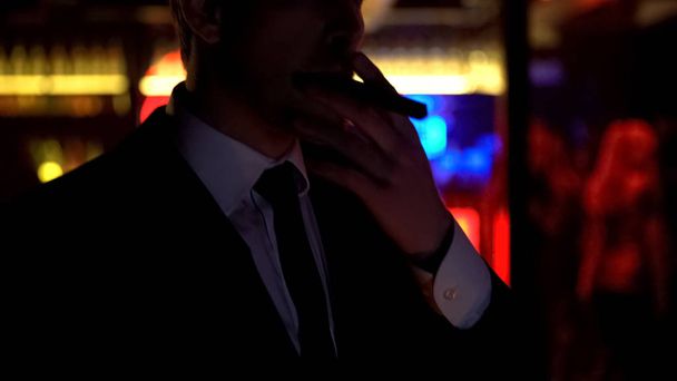 Successful businessman smoking cigar, enjoying evening in elite strip club - Foto, imagen