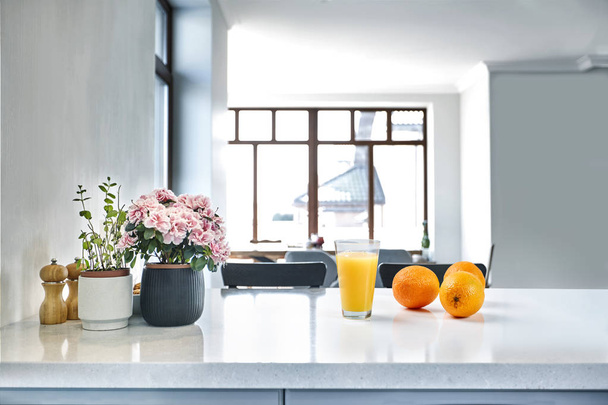 Étvágygerjesztő édes narancs leve és egy ivás szemüveg állva egy fehér asztal, a konyha, reggeli. - Fotó, kép