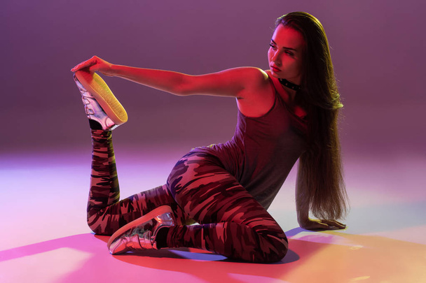 Привлекательная юная брюнетка в студии танцует танец задницы на темном фоне
 - Фото, изображение