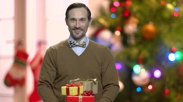 Handsome man with gifts on abstract Christmas background. - Metraje, vídeo