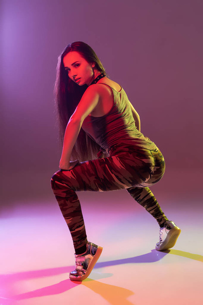 Atractiva joven morena en el estudio bailando Booty dance sobre un fondo oscuro
 - Foto, imagen